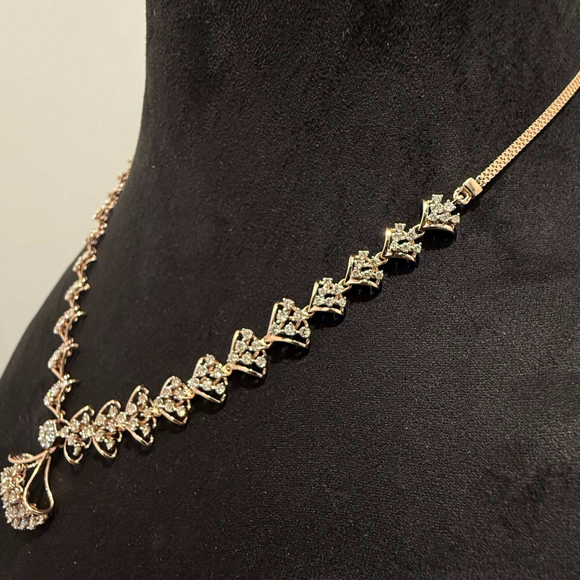 A luxurious gold diamond necklace with earrings set, displayed on a mannequin bust.