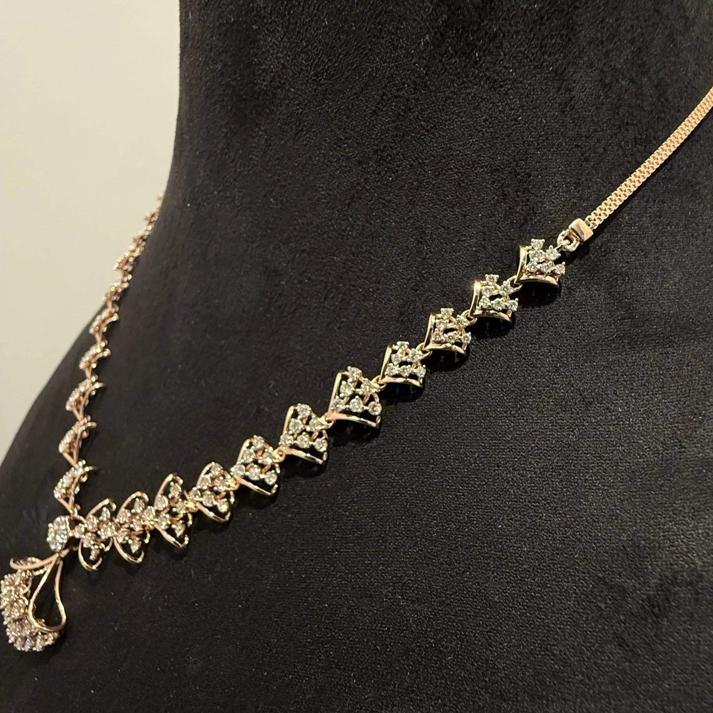 A luxurious gold diamond necklace with earrings set, displayed on a mannequin bust.