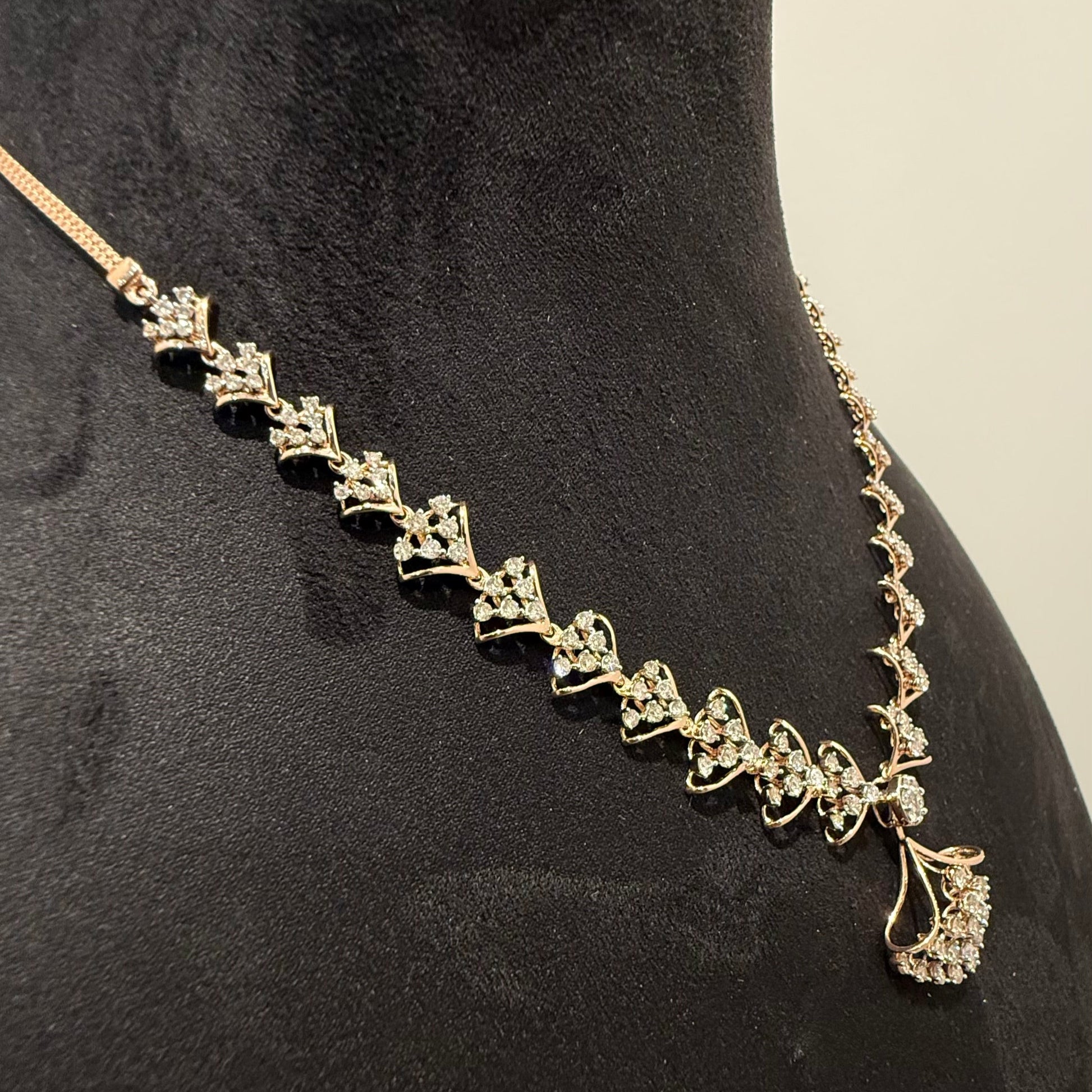 A luxurious gold diamond necklace with earrings set, displayed on a mannequin bust.