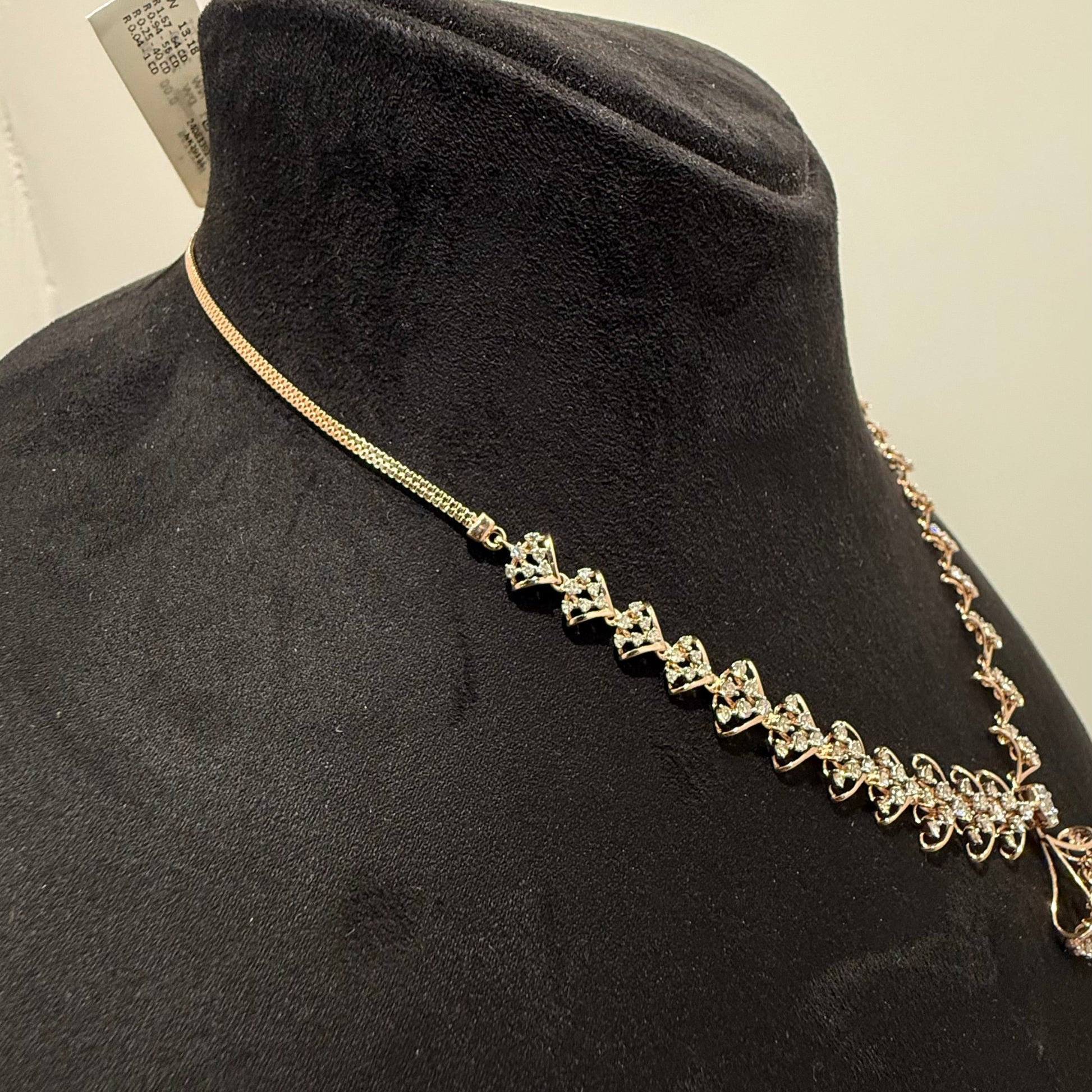 A luxurious gold diamond necklace with earrings set, displayed on a mannequin bust.