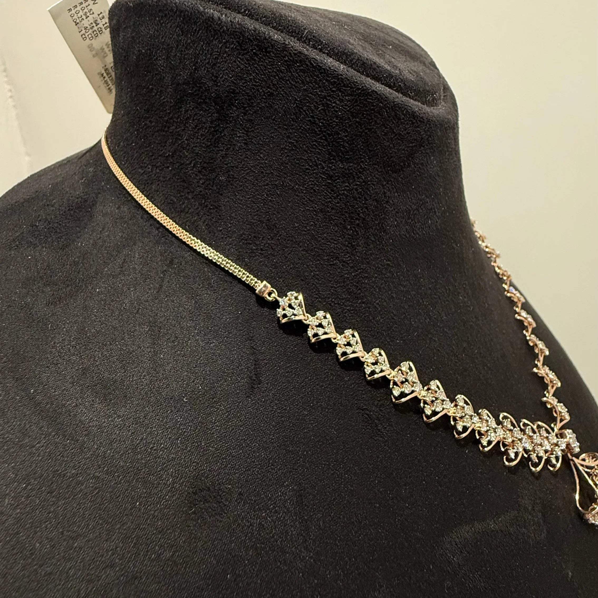 A luxurious gold diamond necklace with earrings set, displayed on a mannequin bust.