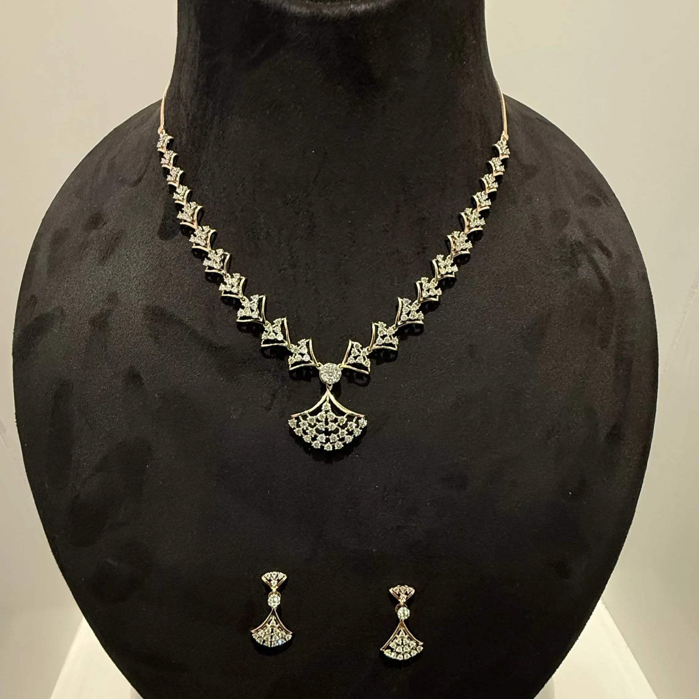 A luxurious gold diamond necklace with earrings set, displayed on a mannequin bust.