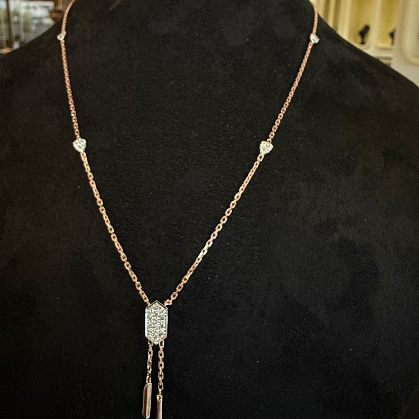 Modern diamond necklace set with hexagon pendant on display.