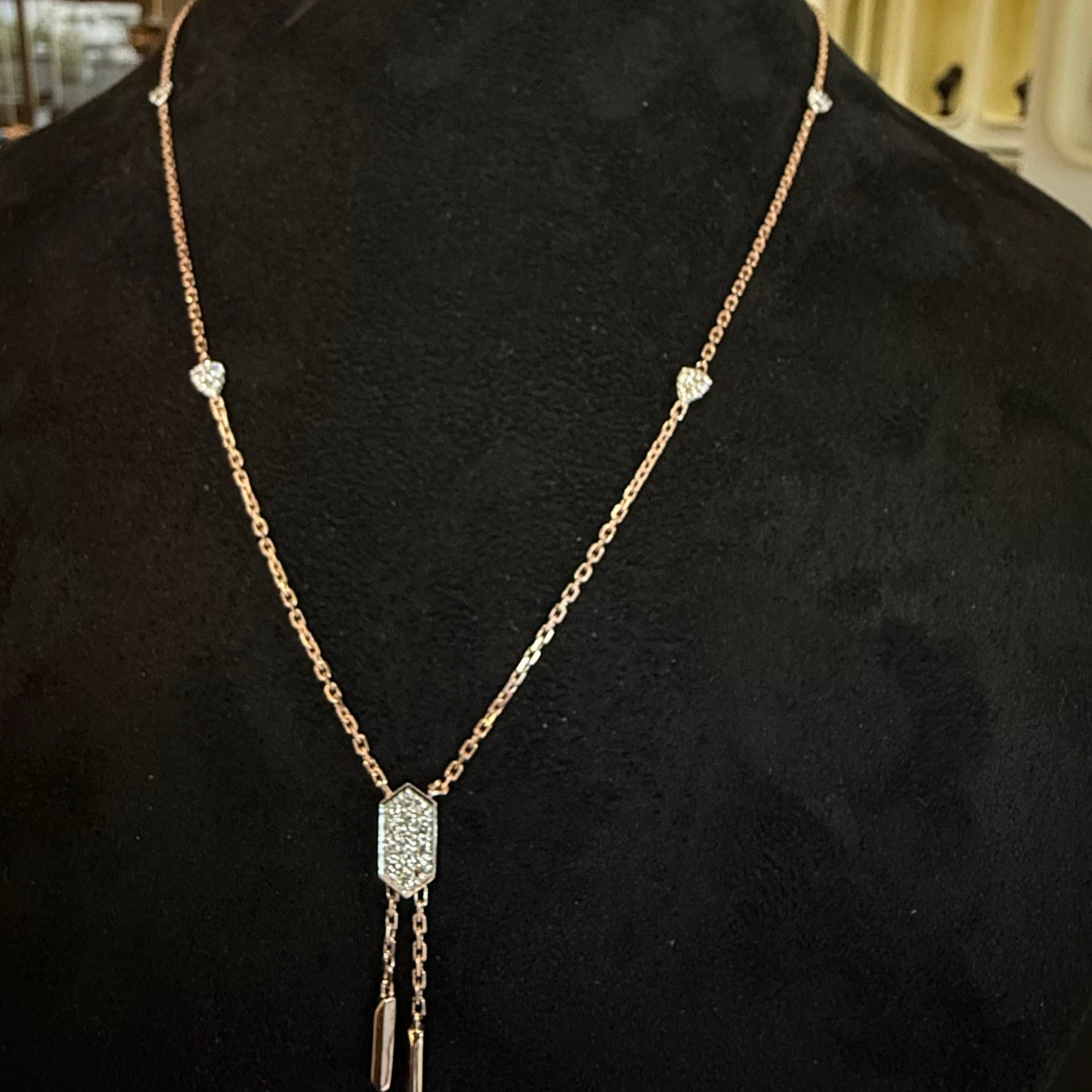 Modern diamond necklace set with hexagon pendant on display.
