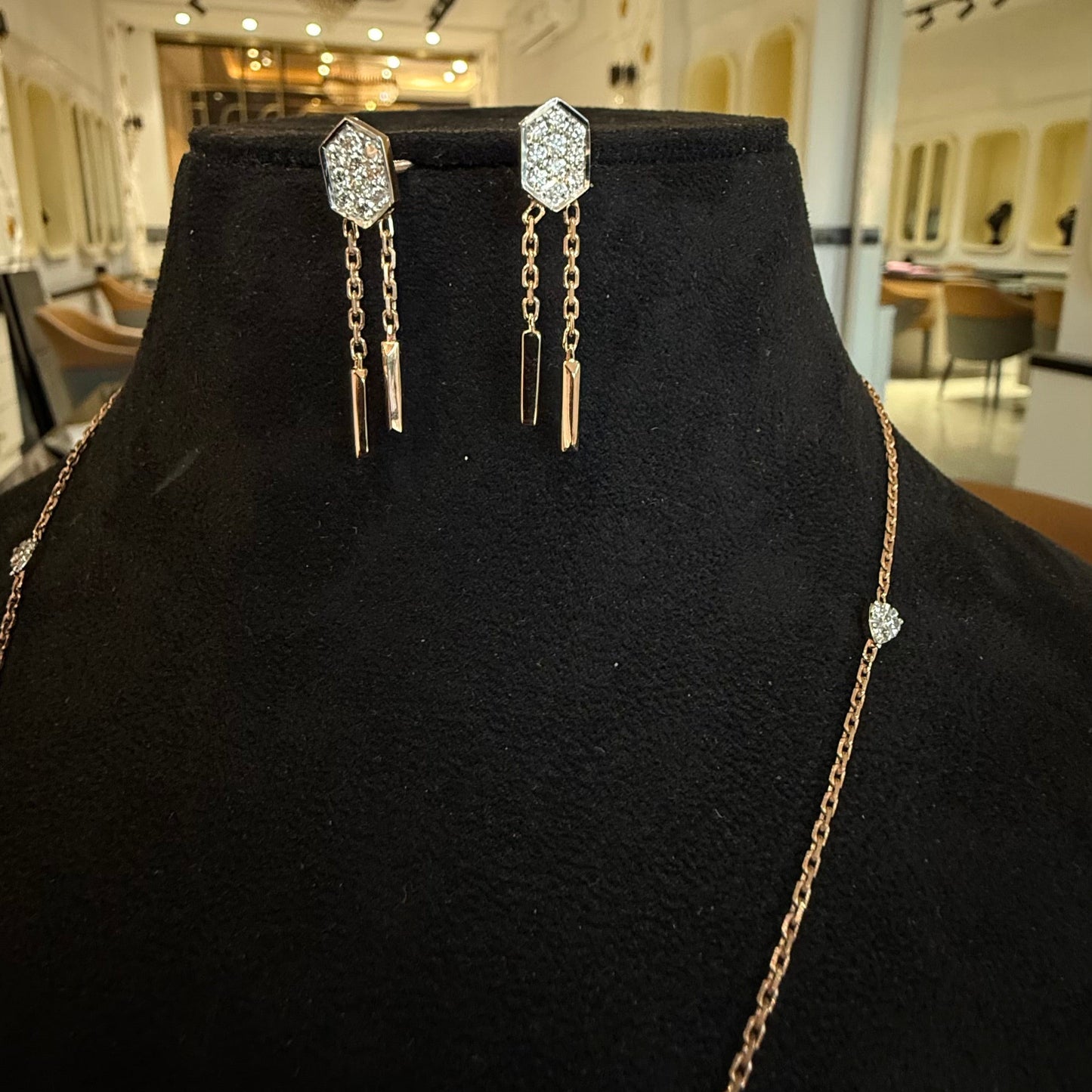 Modern diamond necklace set with hexagon pendant and matching drop earrings on display.