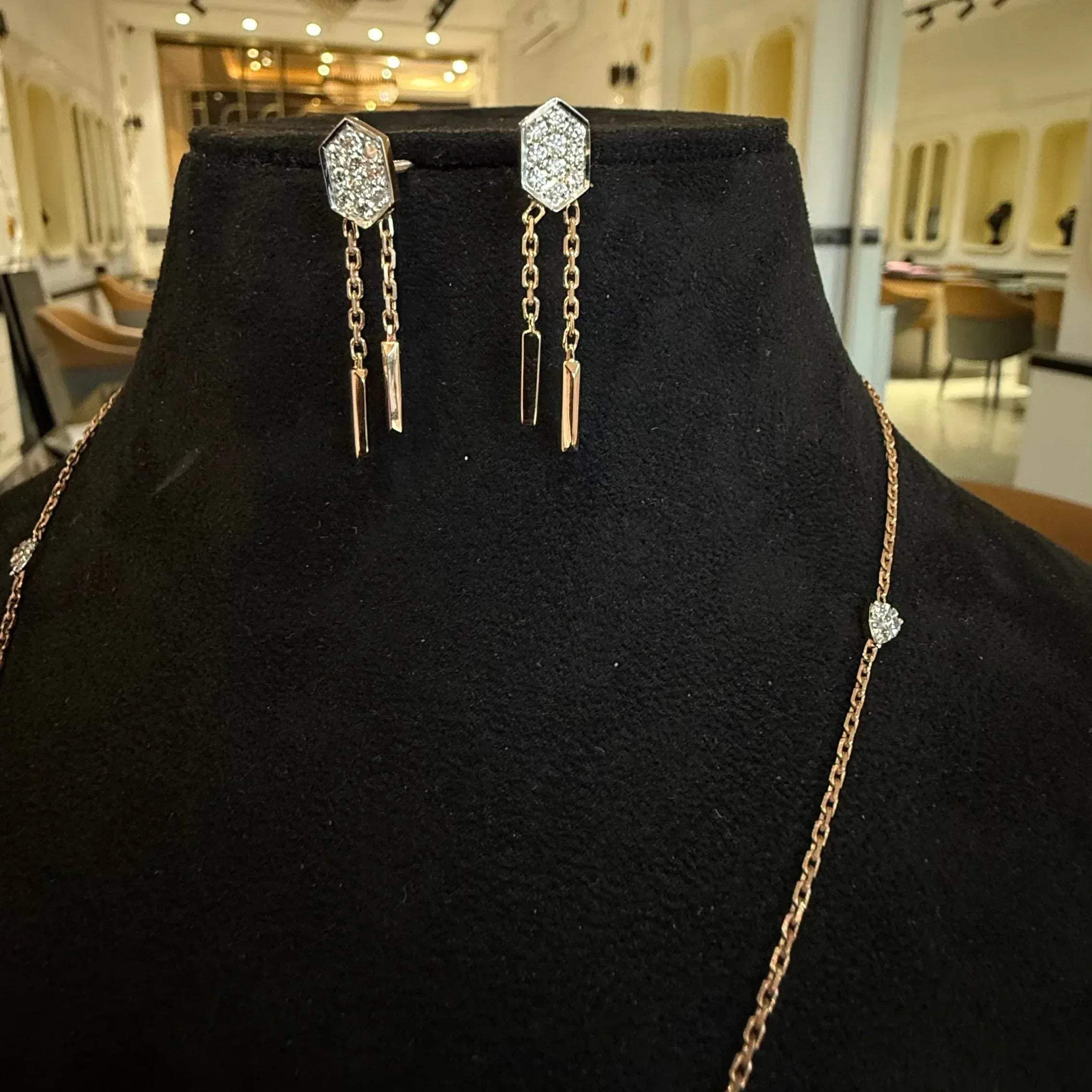 Modern diamond necklace set with hexagon pendant and matching drop earrings on display.