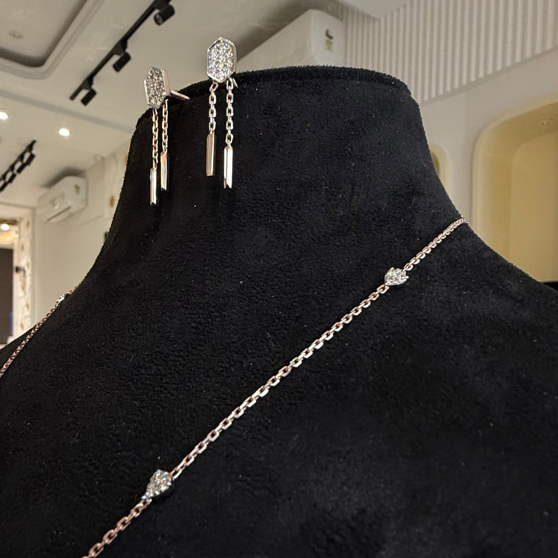 Modern diamond necklace set with hexagon pendant and matching drop earrings on display.