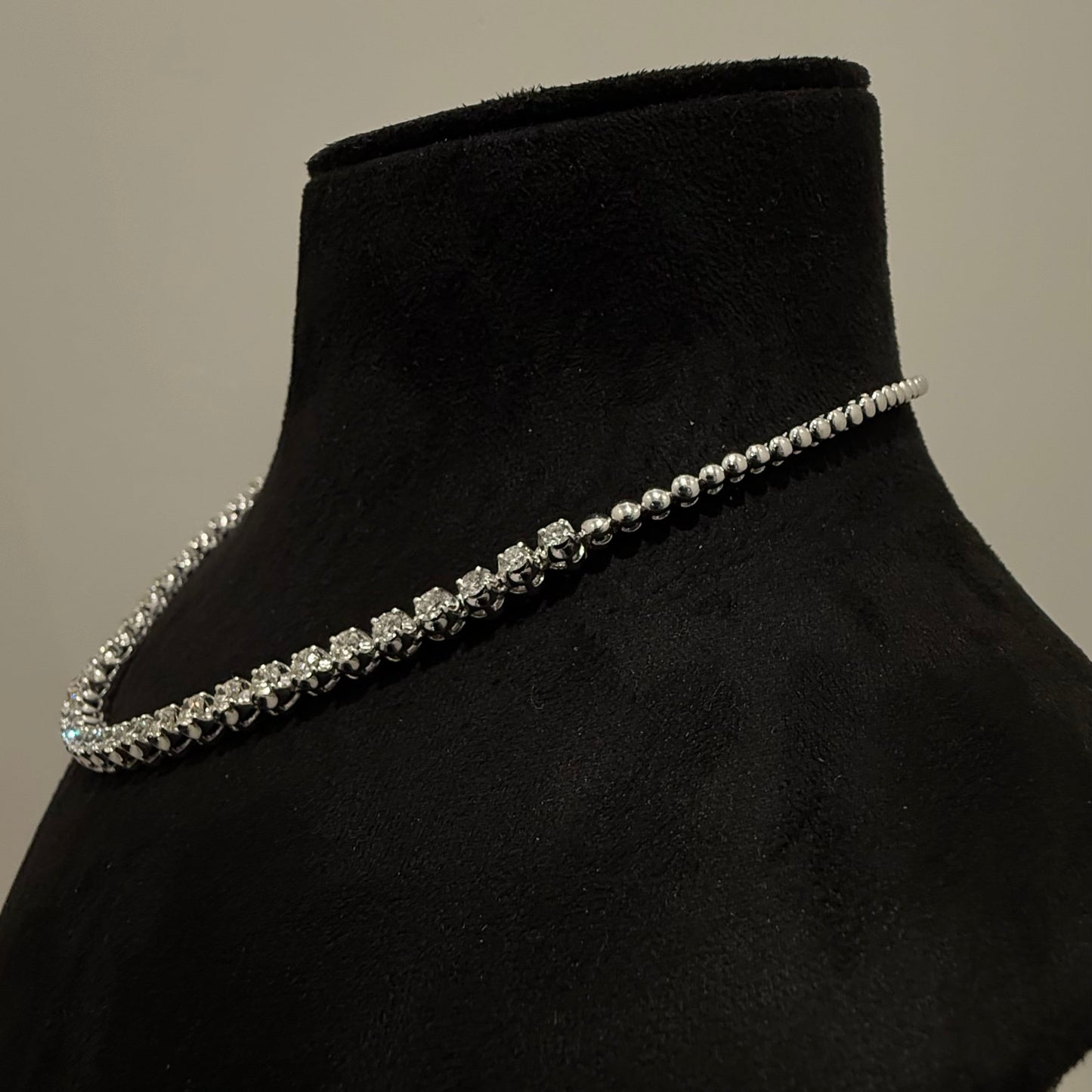 Elegant round cut diamond necklace set displayed on a black mannequin stand.