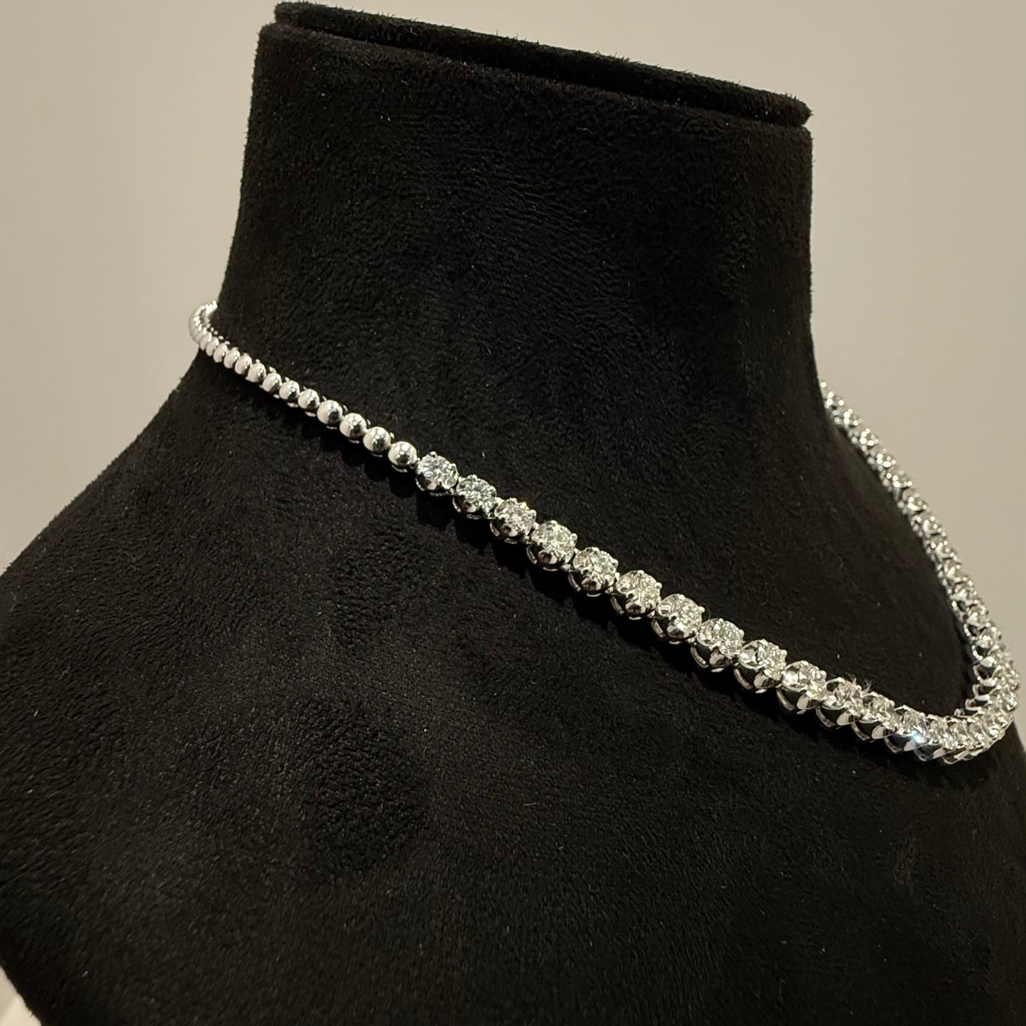 Elegant round cut diamond necklace set displayed on a black mannequin stand.