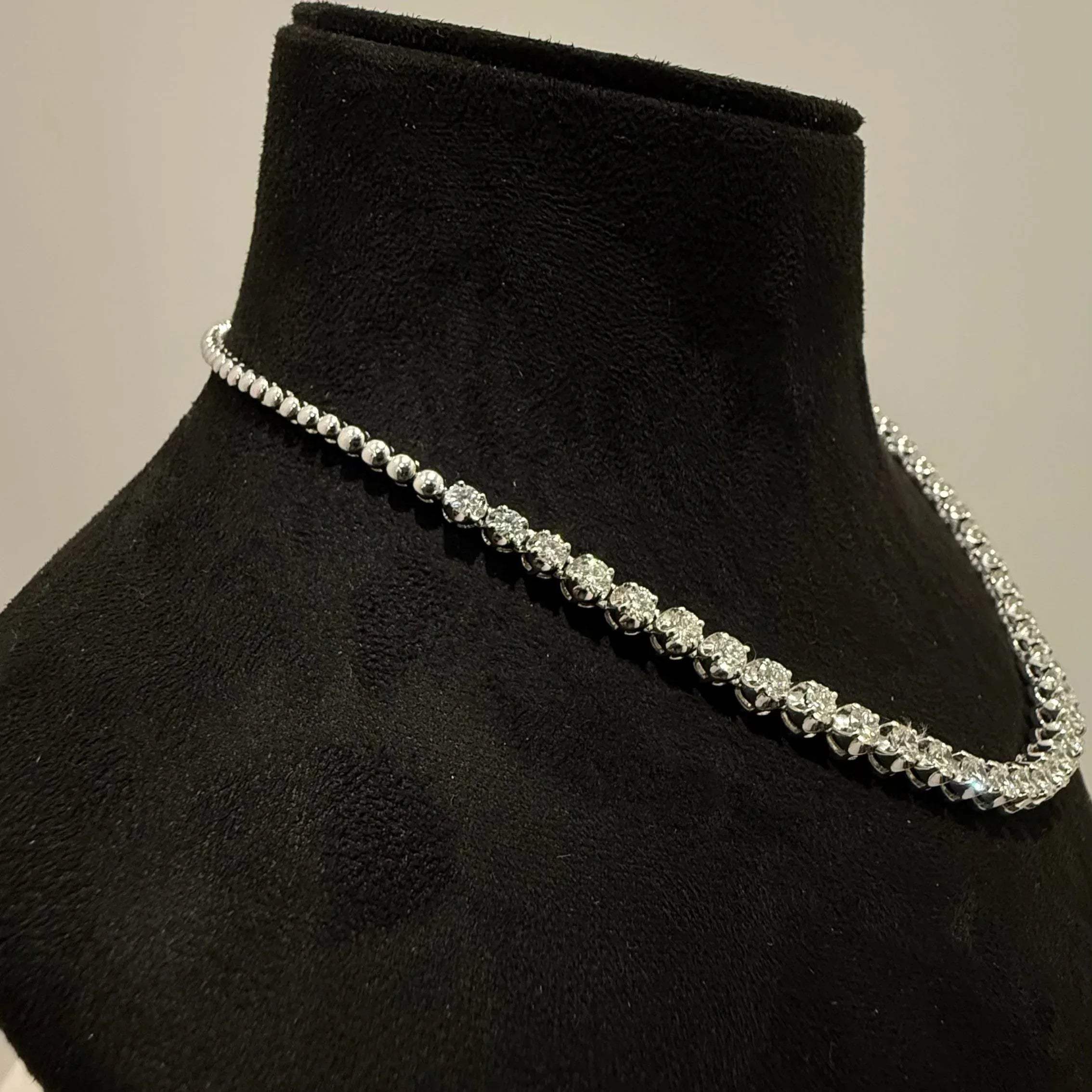 Elegant round cut diamond necklace set displayed on a black mannequin stand.