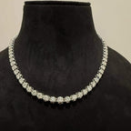 Elegant round cut diamond necklace set displayed on a black mannequin stand.