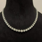 Elegant round cut diamond necklace set displayed on a black mannequin stand.