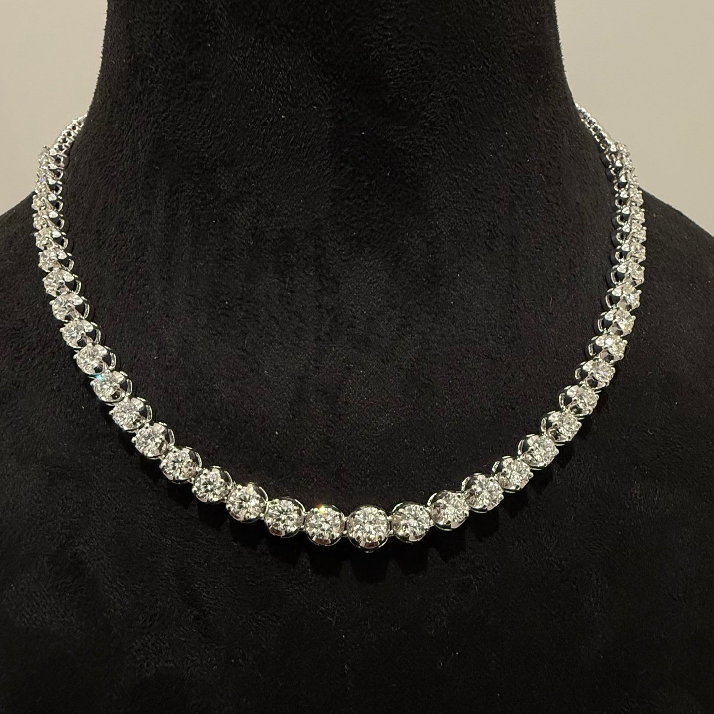 Elegant round cut diamond necklace set displayed on a black mannequin stand.