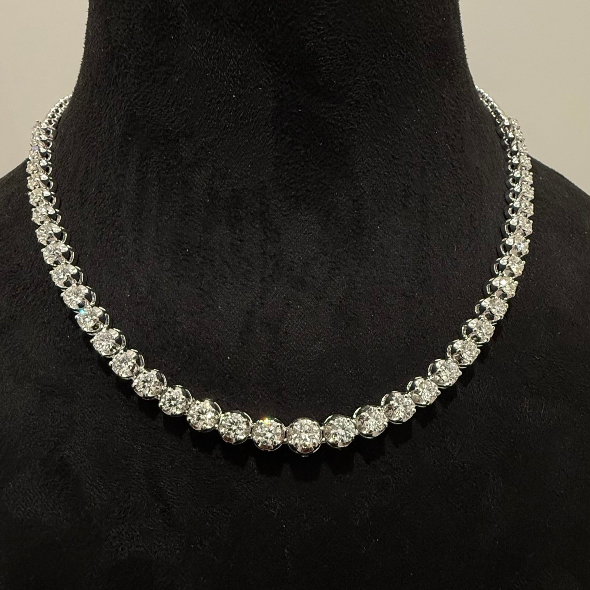Elegant round cut diamond necklace set displayed on a black mannequin stand.