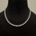 Elegant round cut diamond necklace set displayed on a black mannequin stand.