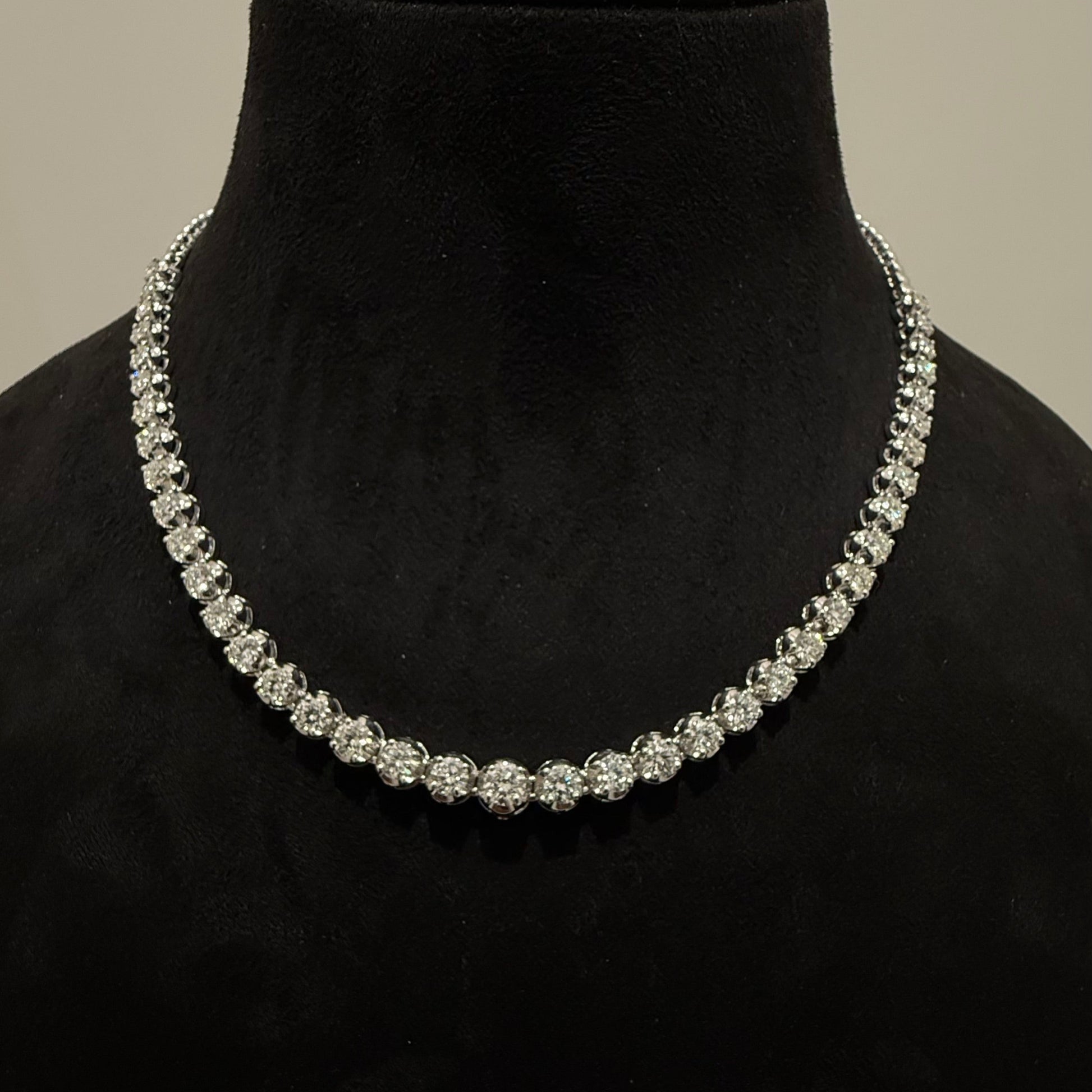 Elegant round cut diamond necklace set displayed on a black mannequin stand.
