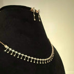 A mannequin showcasing a minimalist diamond necklace and earrings set in gold.