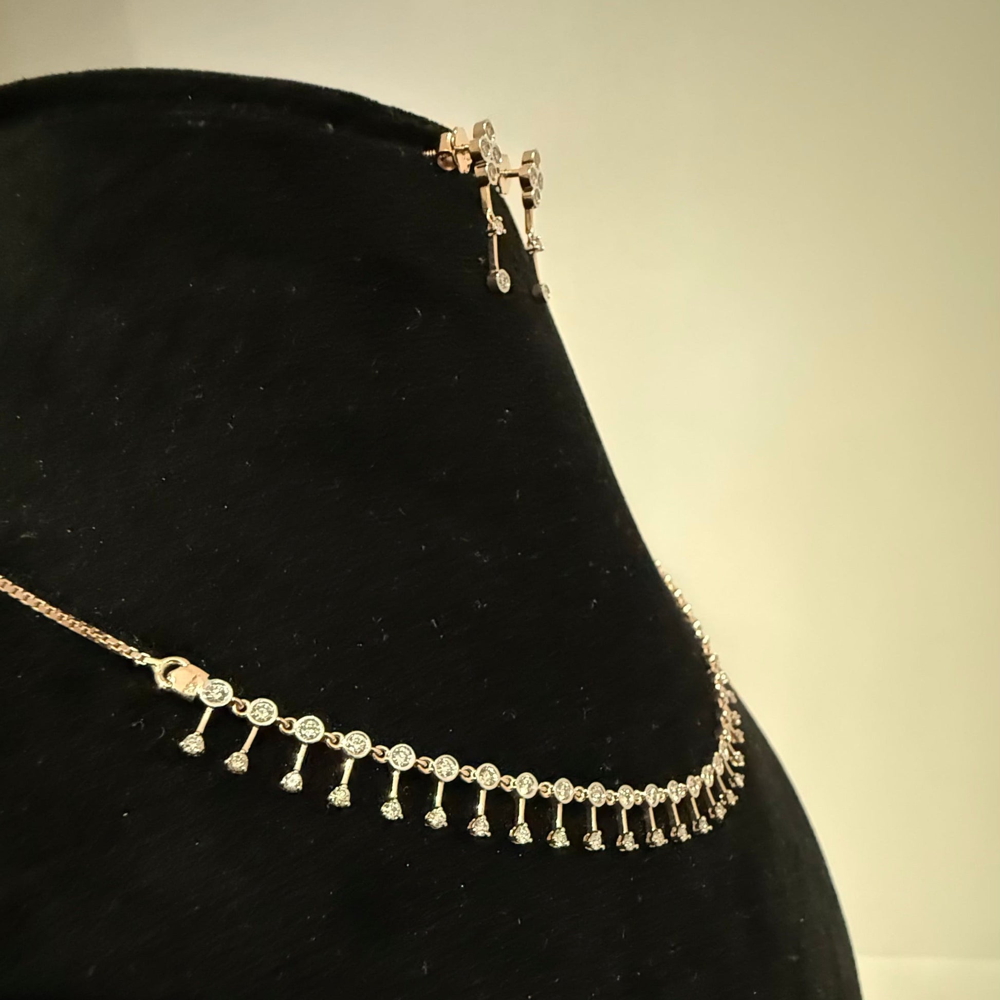 A mannequin showcasing a minimalist diamond necklace and earrings set in gold.