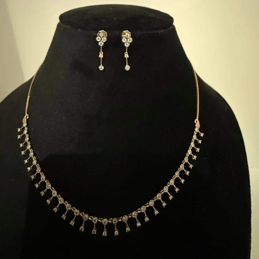 A mannequin showcasing a minimalist diamond necklace and earrings set in gold.