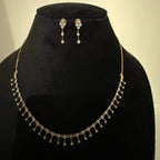 A mannequin showcasing a minimalist diamond necklace and earrings set in gold.