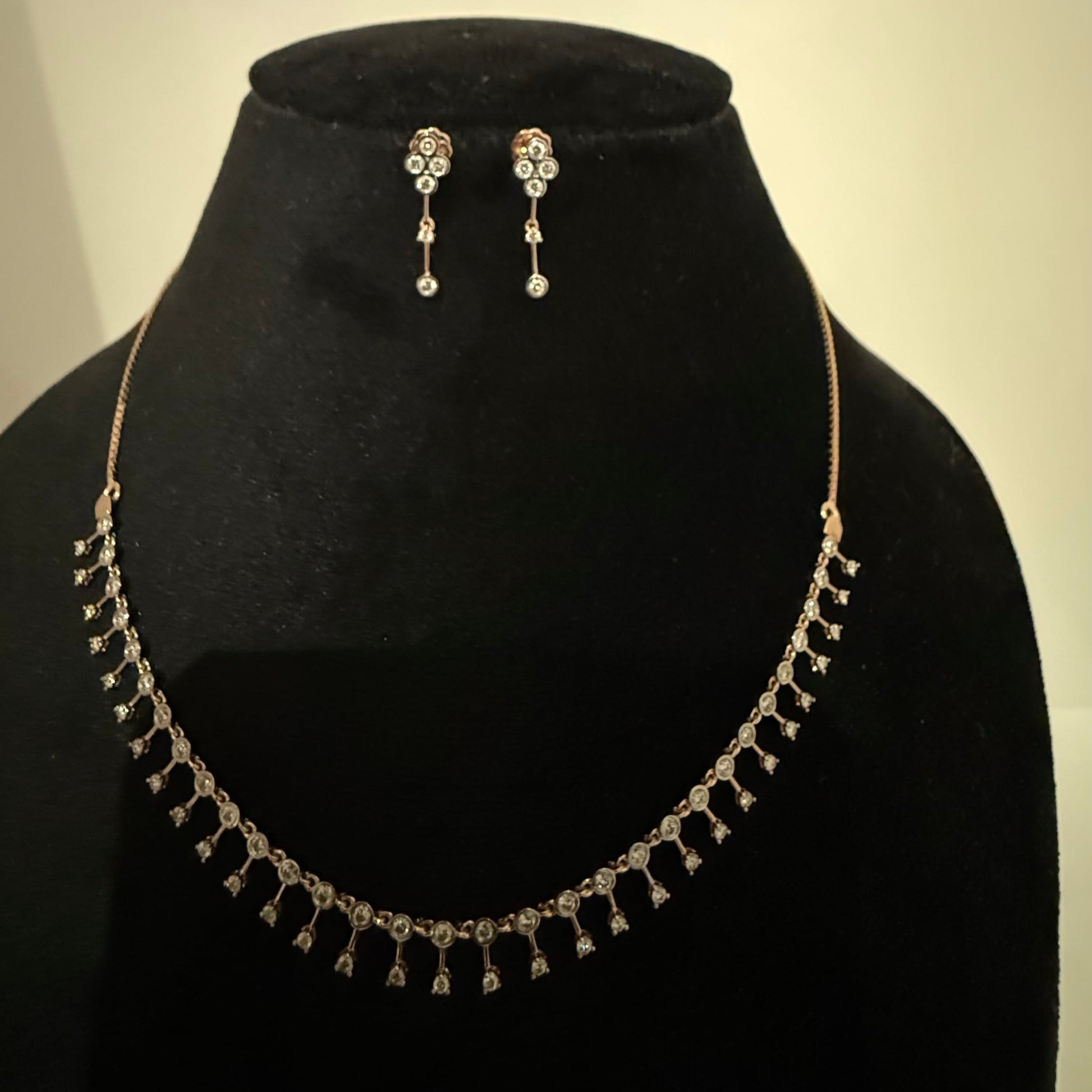 A mannequin showcasing a minimalist diamond necklace and earrings set in gold.