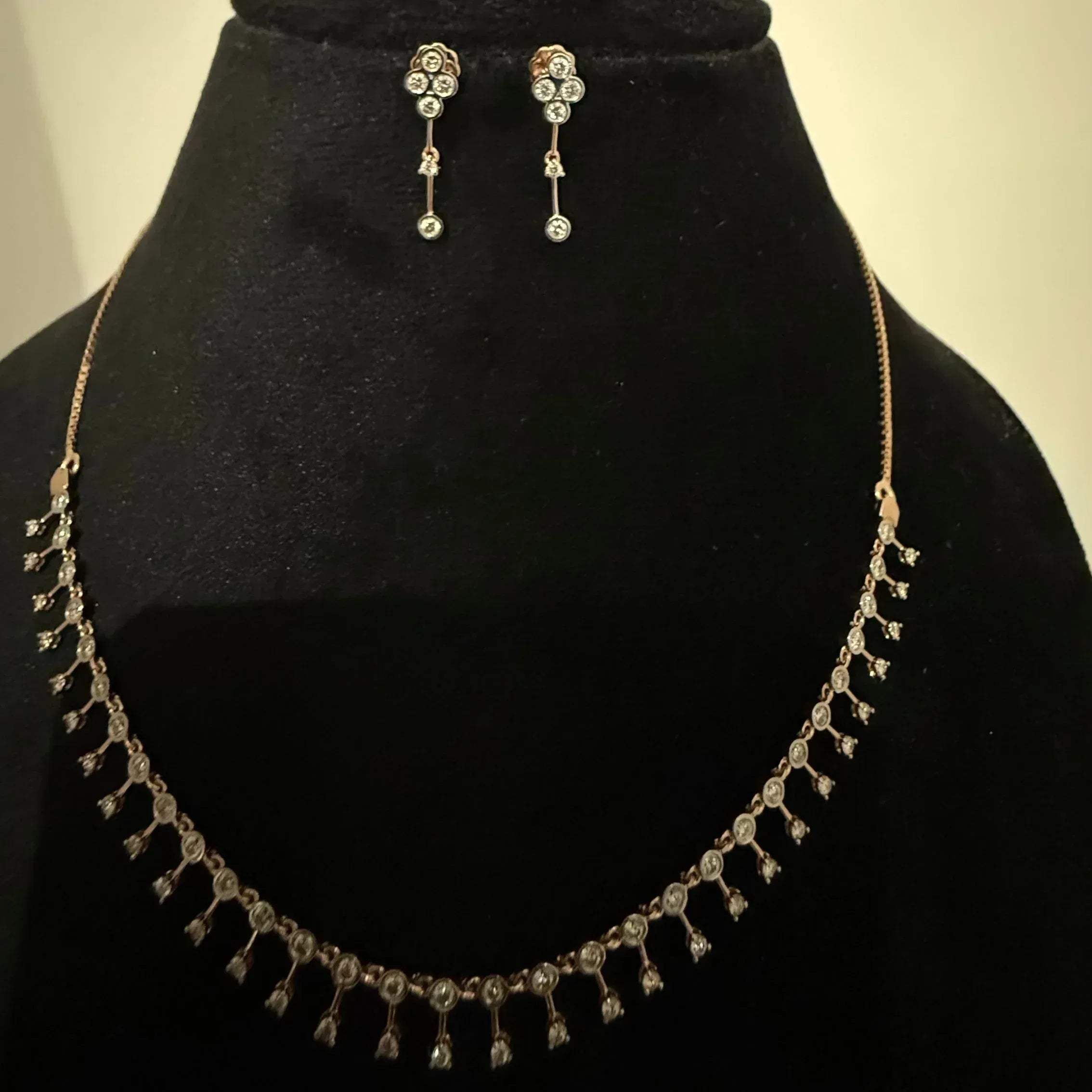 A mannequin showcasing a minimalist diamond necklace and earrings set in gold.