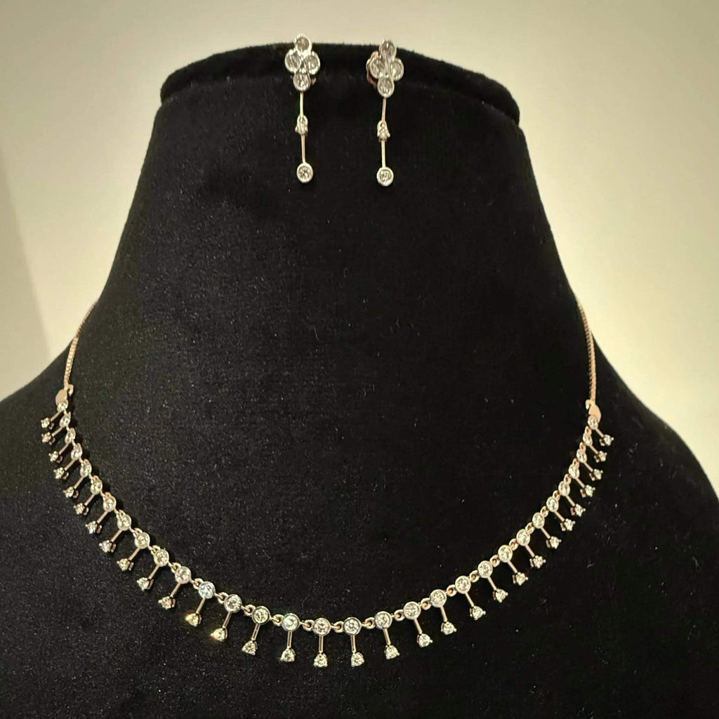 A mannequin showcasing a minimalist diamond necklace and earrings set in gold.