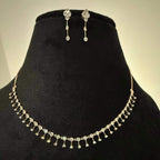 A mannequin showcasing a minimalist diamond necklace and earrings set in gold.
