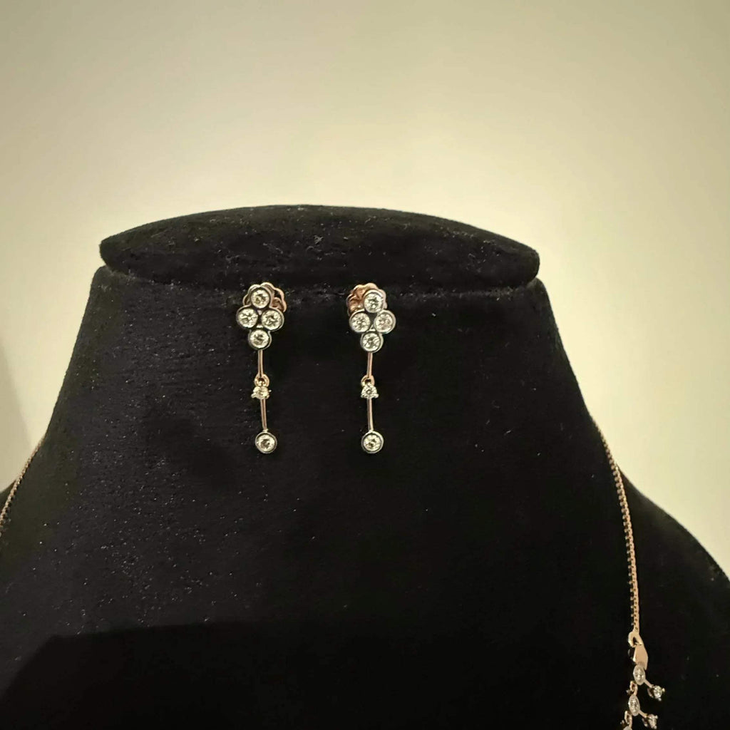 A mannequin showcasing a minimalist diamond necklace and earrings set in gold.