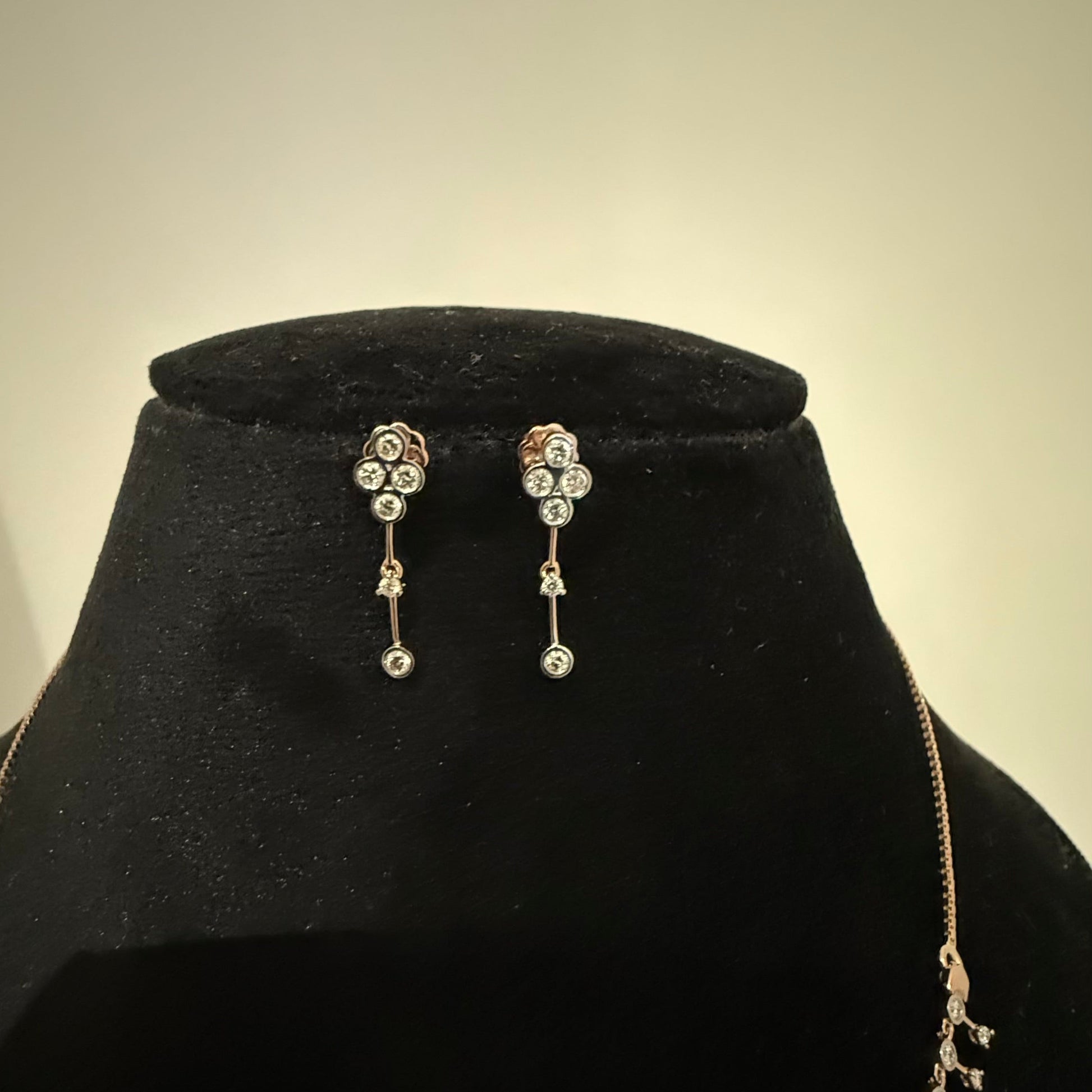 A mannequin showcasing a minimalist diamond necklace and earrings set in gold.