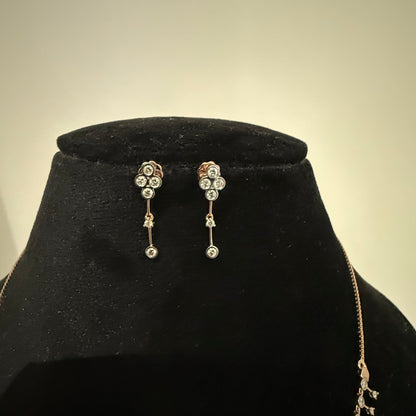 A mannequin showcasing a minimalist diamond necklace and earrings set in gold.