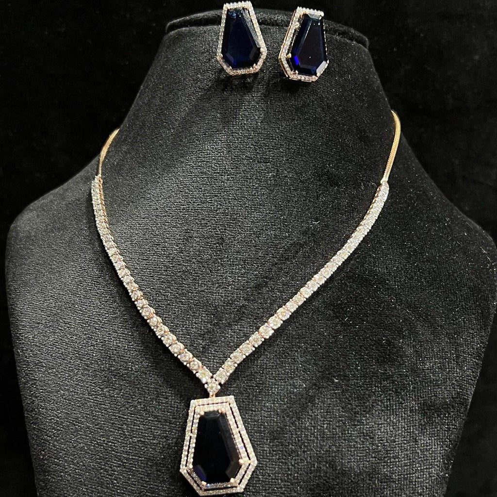 A diamond necklace set featuring a striking geometric deep blue gemstone pendant with matching earrings, all displayed on a black velvet background.
