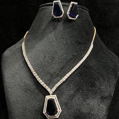 A diamond necklace set featuring a striking geometric deep blue gemstone pendant with matching earrings, all displayed on a black velvet background.