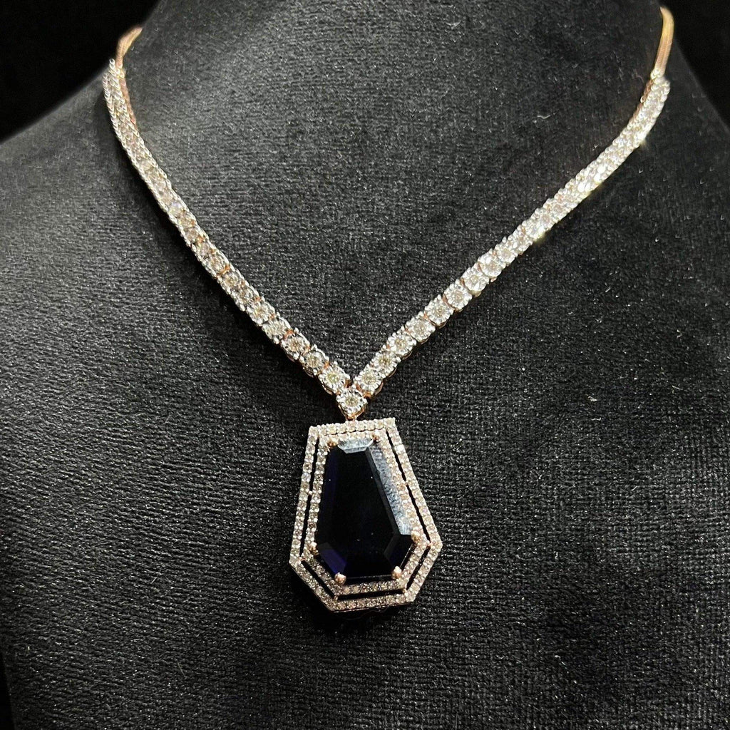 A diamond necklace set featuring a striking geometric deep blue gemstone pendant, all displayed on a black velvet background.