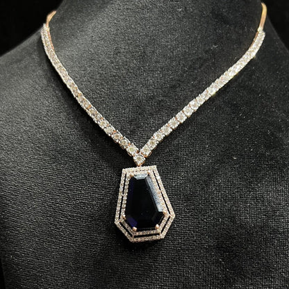 A diamond necklace set featuring a striking geometric deep blue gemstone pendant, all displayed on a black velvet background.