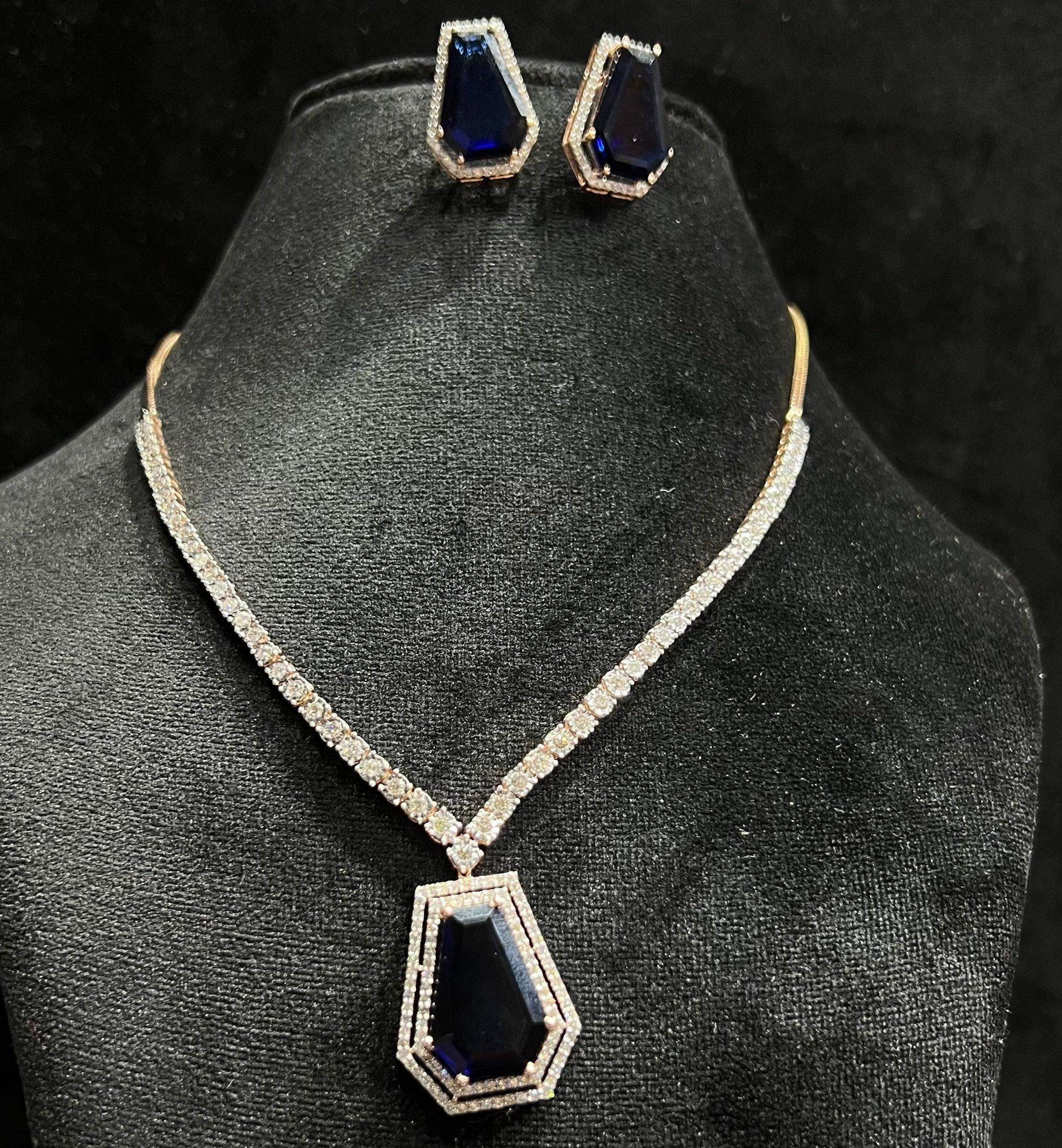 A gold diamond necklace with a geometric pattern and a pair of matching earrings, displayed on a black mannequin bust.