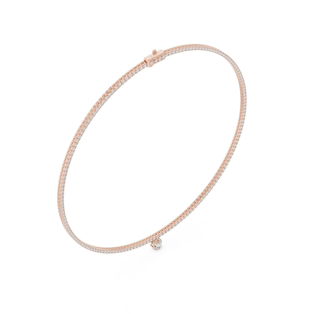 Gold and diamond tennis necklace with a small pear shape diamond pendant on a white background