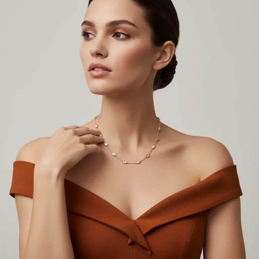 Woman wearing a brown off-shoulder top and diamond necklace against a neutral background.