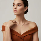Woman wearing a brown off-shoulder top and diamond necklace against a neutral background.