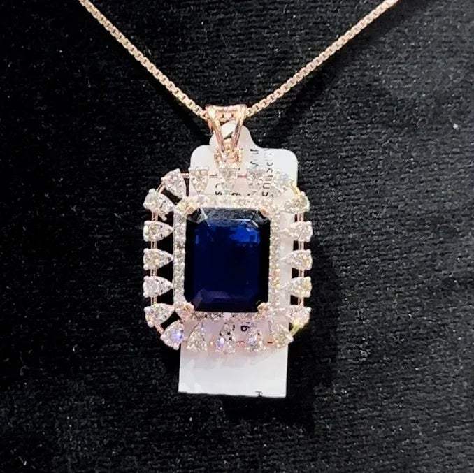 A gold diamond pendant with a blue center stone surrounded by smaller white diamonds, attached to a gold chain for earrings.