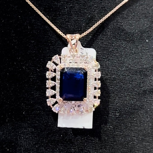 A gold diamond pendant with a blue center stone surrounded by smaller white diamonds, attached to a gold chain for earrings.