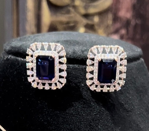 gold diamond earrings with a blue center stone surrounded by smaller white diamonds