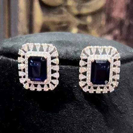 gold diamond earrings with a blue center stone surrounded by smaller white diamonds