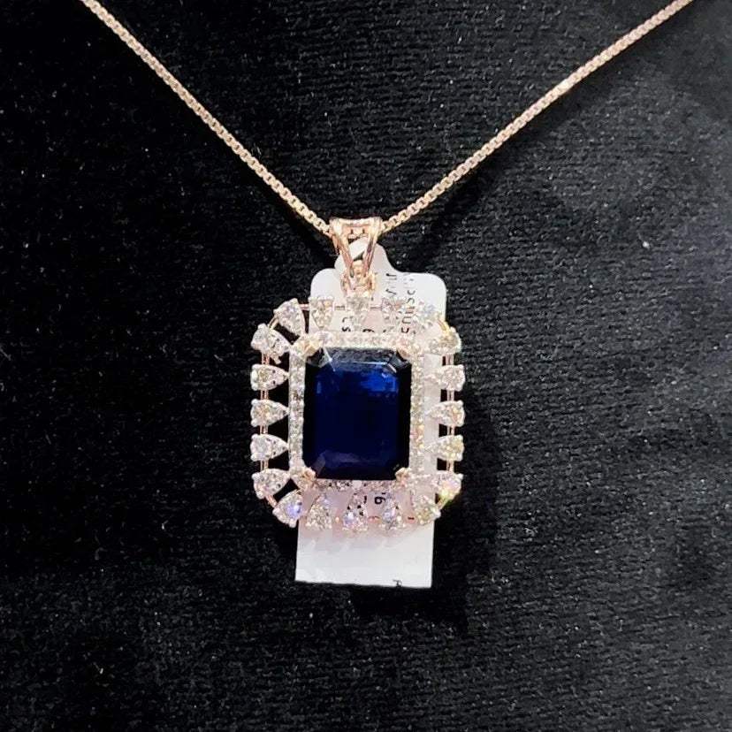 A gold diamond pendant with a blue center stone surrounded by smaller white diamonds, attached to a gold chain for earrings.