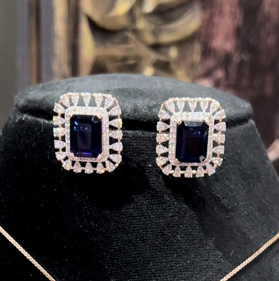 gold diamond earrings with a blue center stone surrounded by smaller white diamonds