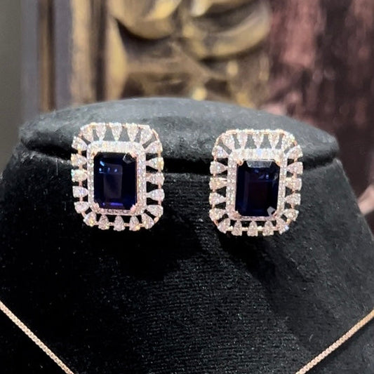 gold diamond earrings with a blue center stone surrounded by smaller white diamonds