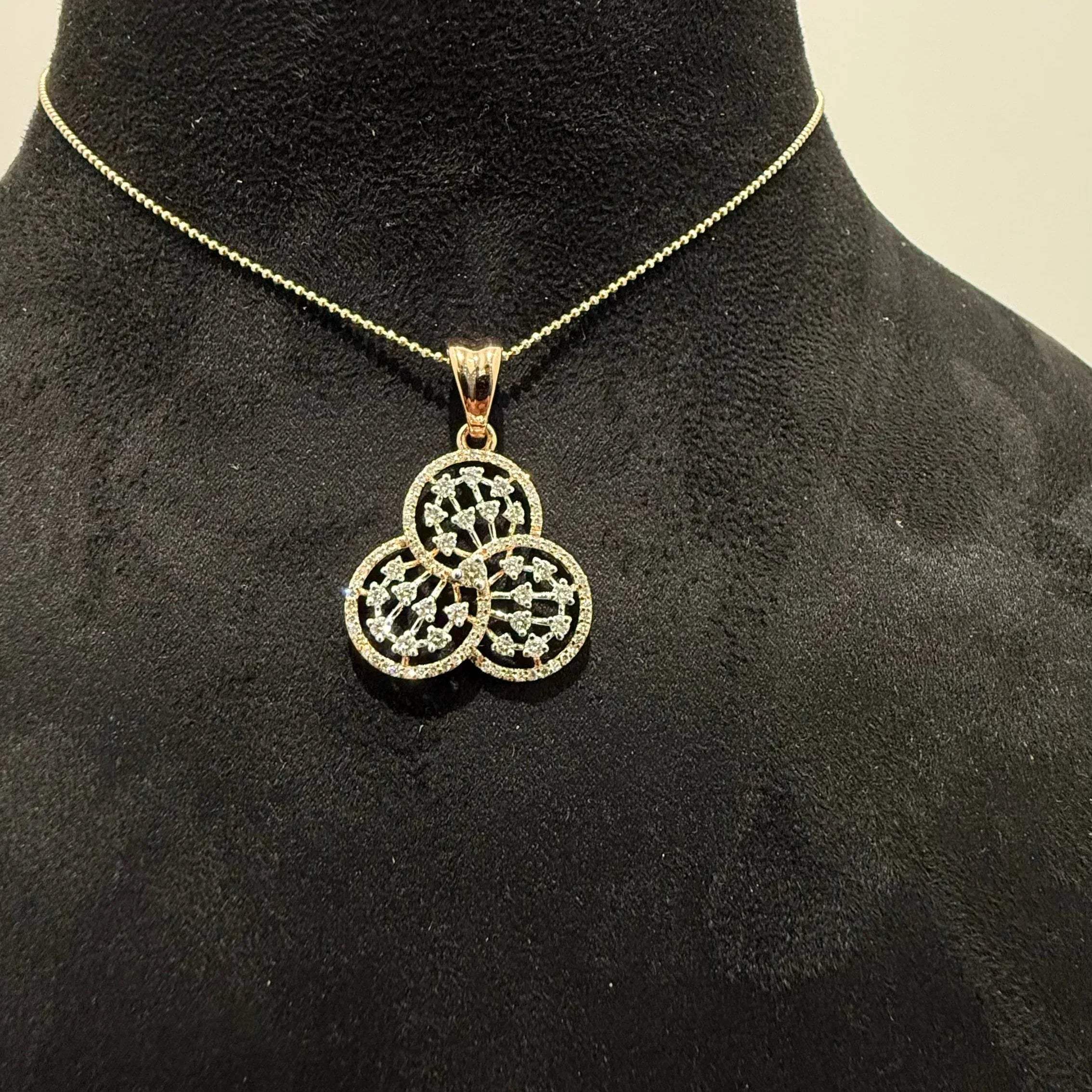 A gold diamond pendant with a floral design, displayed on a black mannequin necklace stand.