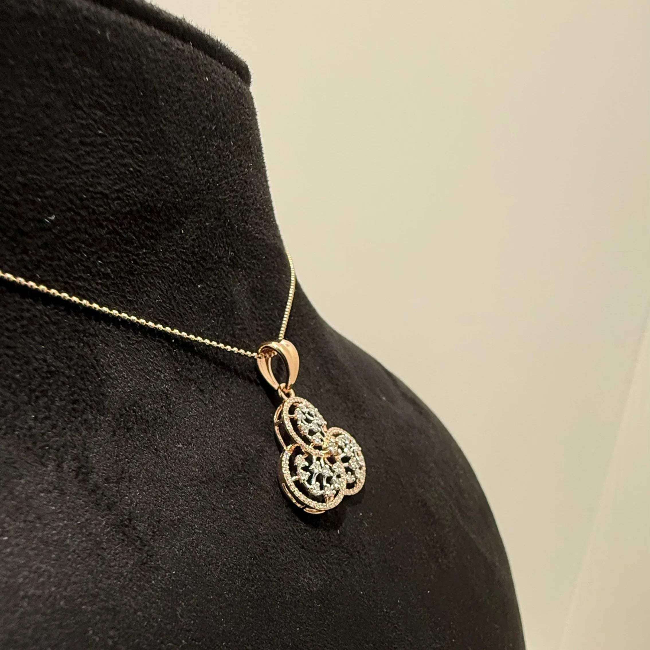 A gold diamond pendant with a floral design, displayed on a black mannequin necklace stand.