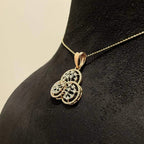A gold diamond pendant with a floral design, displayed on a black mannequin necklace stand.
