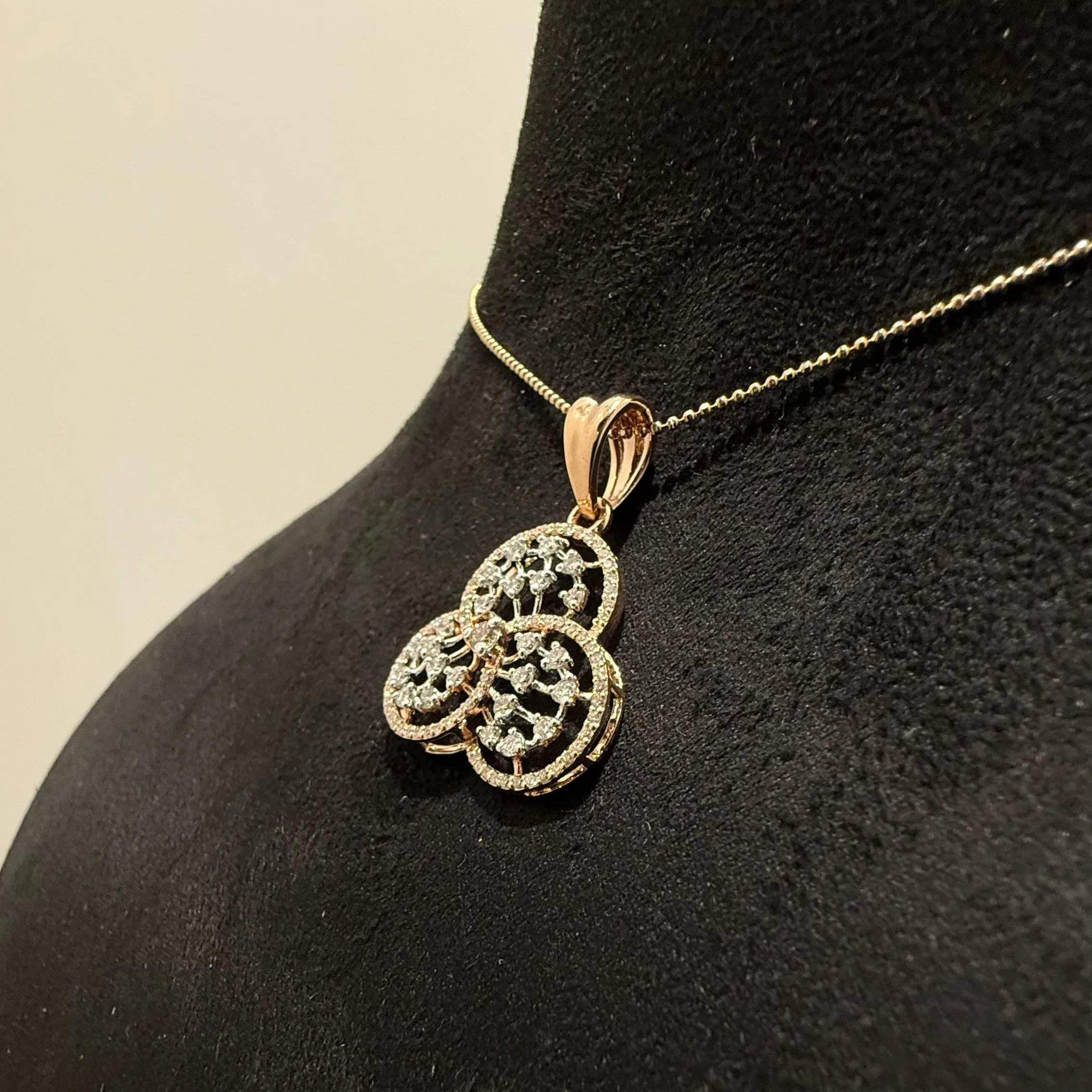 A gold diamond pendant with a floral design, displayed on a black mannequin necklace stand.